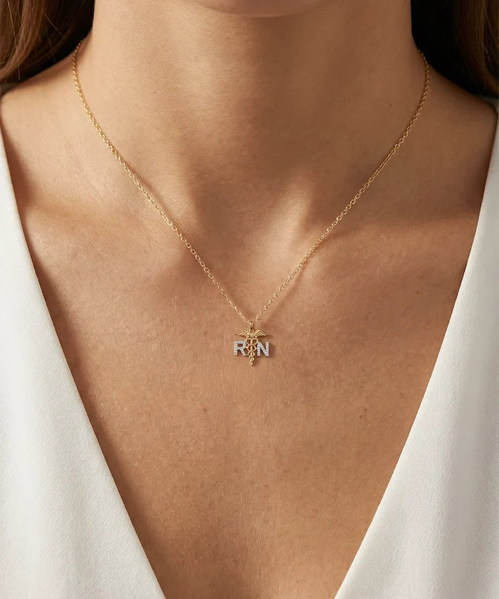Gold necklace with a pendant on a person wearing a white top