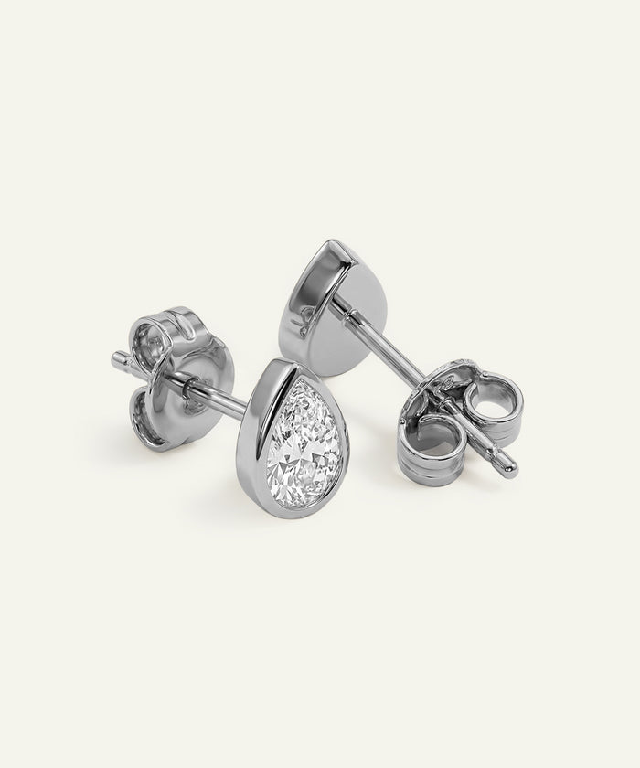 Pair of silver teardrop-shaped stud earrings on a white background