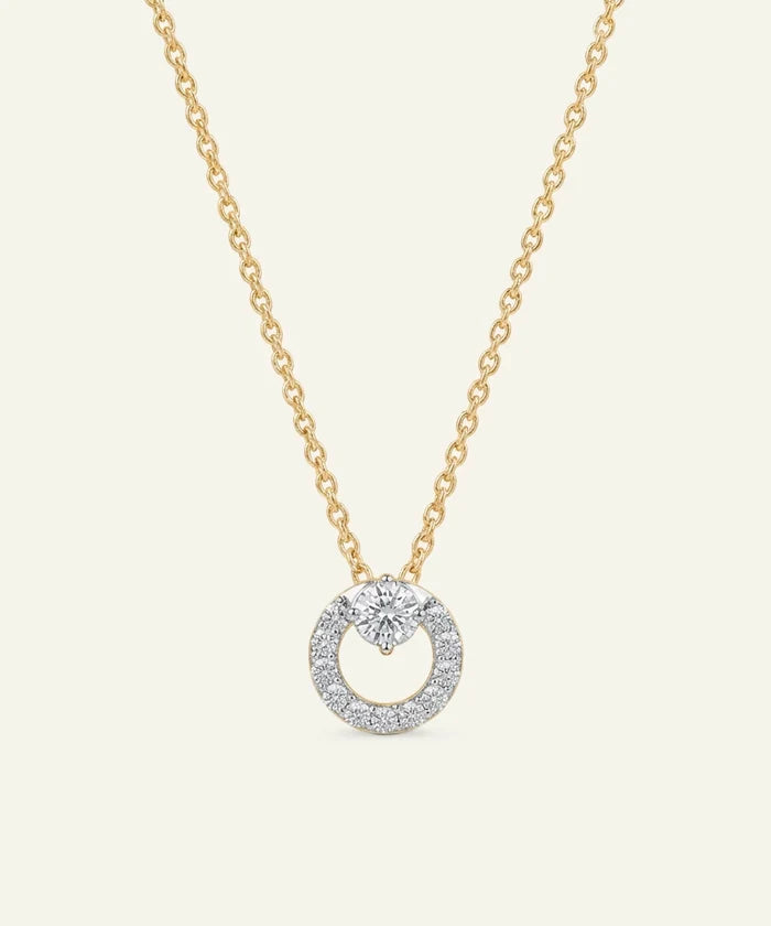 Gold necklace with a diamond pendant on a light beige background