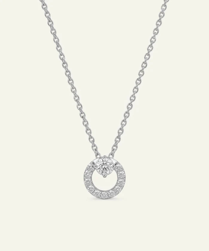 Silver necklace with a round pendant on a light gray background