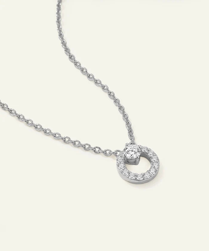 Silver necklace with a round pendant on a light gray background
