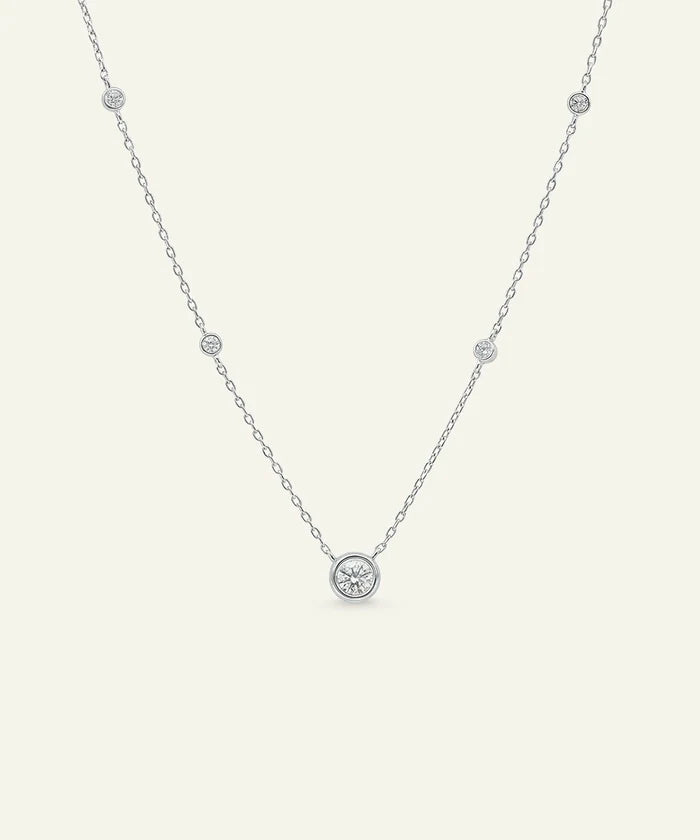 Delicate silver necklace with small round pendants on a light gray background