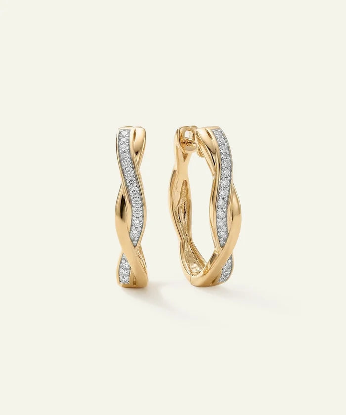 Gold hoop earrings with diamond accents on a light beige background