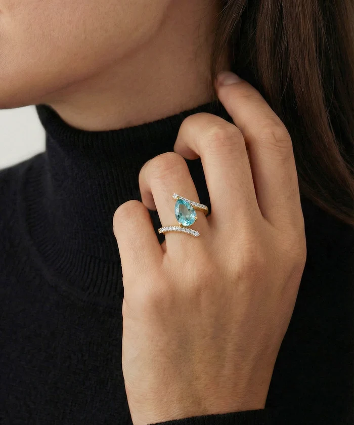 Close-up of a hand wearing two turquoise gemstone rings on a blurred background
