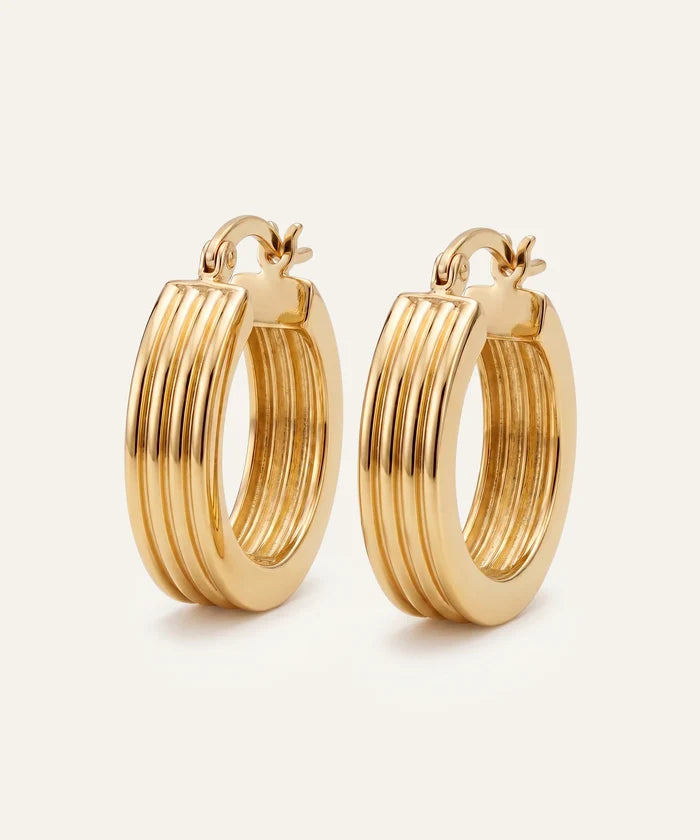 Gold hoop earrings on a light beige background