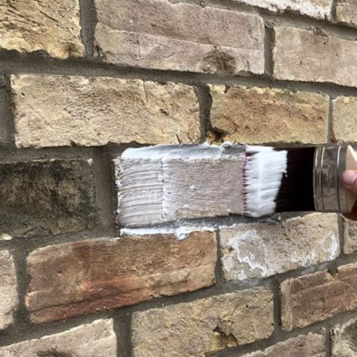 Hand applying Passivhaus Brickseal invisible coating to a brick wall to stop damp and moisture penetration.