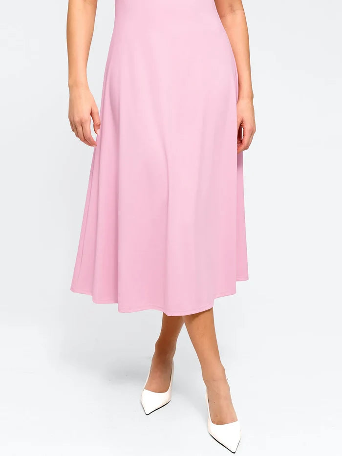 Pink sculpting A-line midi dress with built-in shapewear, paired with white heels.