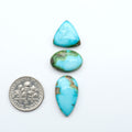 Sonoran Mountain Turquoise cabochons, blue-green color with natural matrix, polished stones on a white background, with a US dime for scale