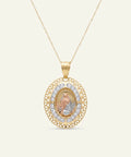 Gold necklace featuring an oval pendant with an intricate filigree outer border and a pave diamond halo. The center showcases a detailed, three-dimensional relief figure of Our Lady of Guadalupe in tri-color gold, suspended on a delicate gold chain.